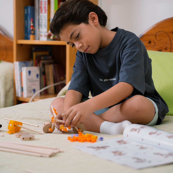Child playing with building Beaver wooden blocks on a bed in a room with books 