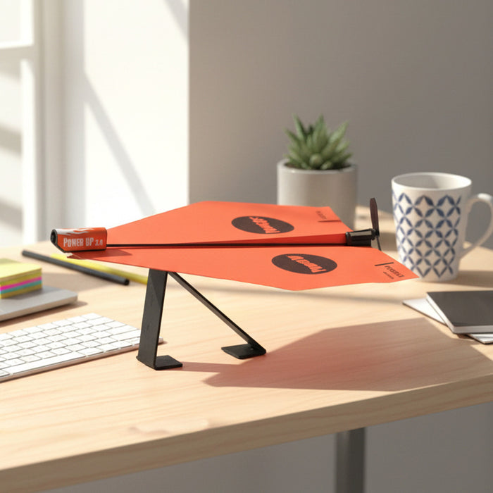 Power up plane stand on a desk with a mug and books in the background