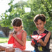 Two children playing with power up toy airplanes outdoors on a sunny day.