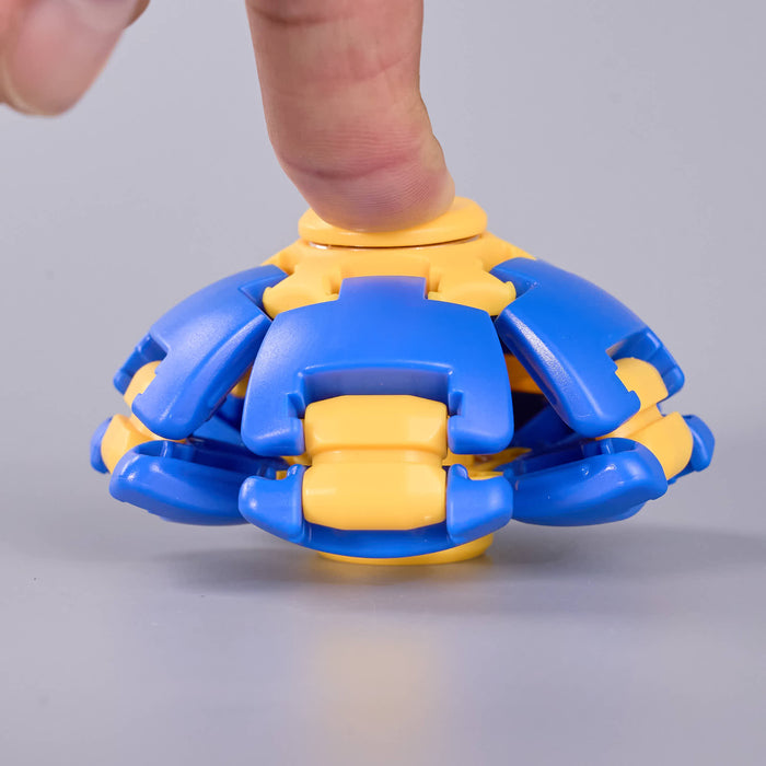 A close-up of a blue and yellow plastic toy being pressed down by a human finger, set against a plain light gray background. Fidgit Sphere Spinner