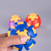 A hand holding a blue and yellow plastic puzzle toy in the foreground, with two more similar toys blurred in the background on a light gray surface. Fidgit Sphere Spinner