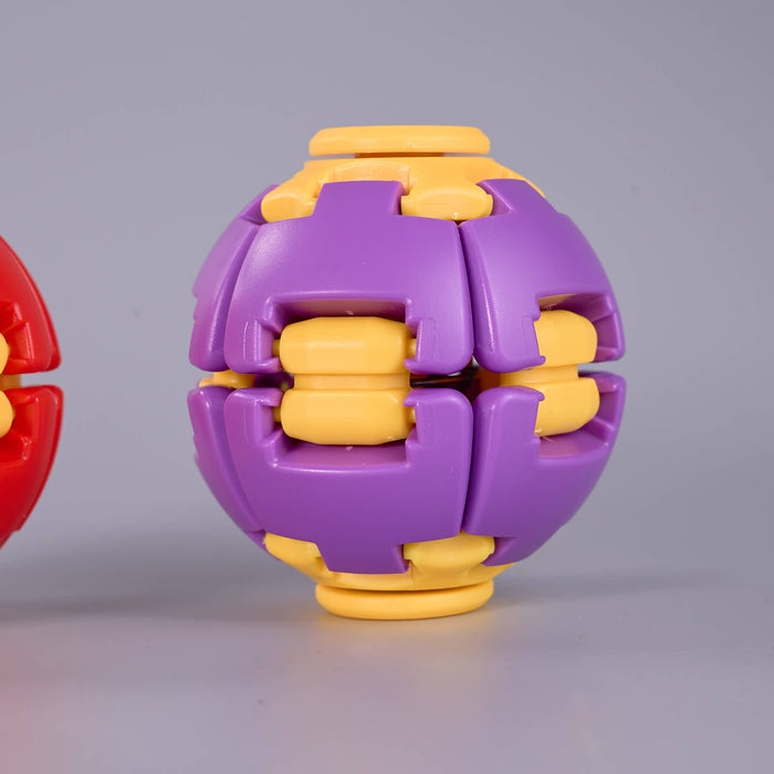 A purple and yellow plastic ball-shaped puzzle toy shown on a light gray studio background, with part of a red version visible at the left edge. Fidgit Sphere Spinner