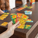 Hand holding colorful game cards with cartoon characters on a wooden table