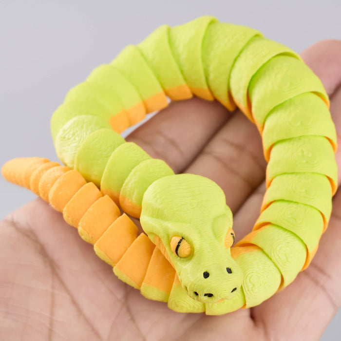 Heebie Jeebies 3D Green and orange snake-shaped toy held in a hand against a gray background
