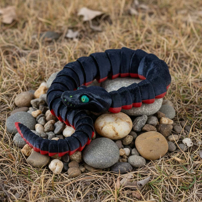 Black and red snake-like toy on stones with a natural background