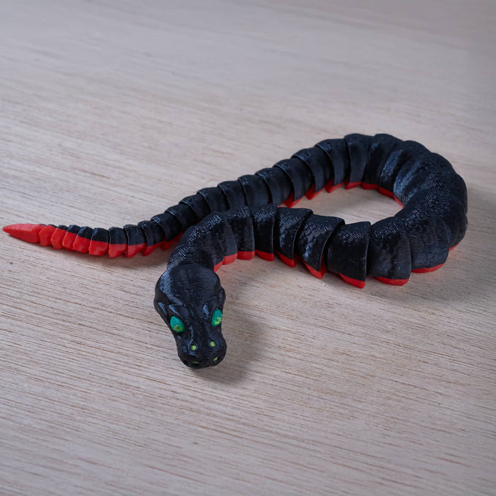 Black and red snake-shaped toy on a wooden surface