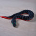 Black and red snake-shaped toy on a wooden surface