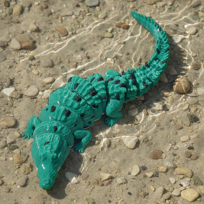 Green toy alligator on a pebbly surface