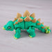 Heebie Jeebies 3D stegosaurus dinosaur with green body and brown spikes on a light wooden surface