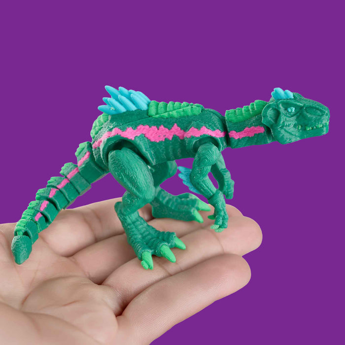 Green toy dinosaur with pink and blue accents held in a hand against a purple background from heebie jeebies