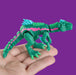 Green toy dinosaur with pink and blue accents held in a hand against a purple background from heebie jeebies