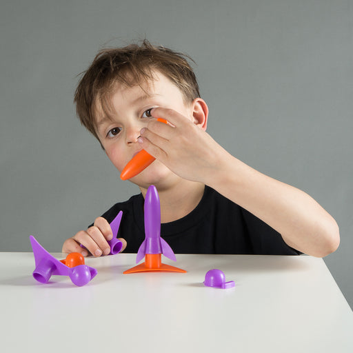 Child playing with toy rocket from heebie Jeebies on a gray background